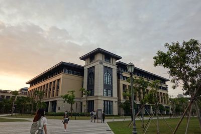 People walking by building against sky