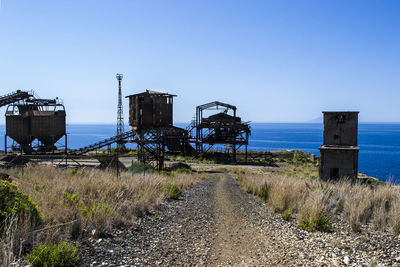 Abandoned metallic structure on land against clear blue sky