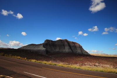 Road by desert against blue sky