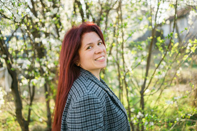 Young woman standing against trees