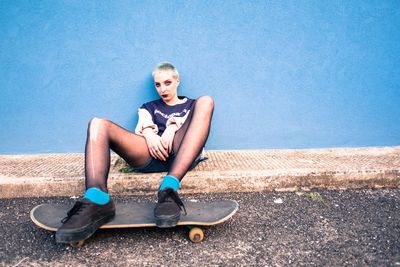 Portrait of young woman sitting on skateboard