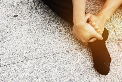 Low section of man holding leg on tiled floor
