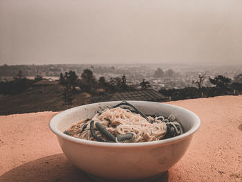 Close-up of bowl on sand against sky