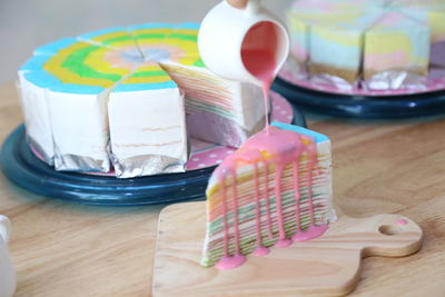 Close-up of hand pouring syrup on cake in plate on table