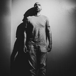 Young man looking away while standing against wall