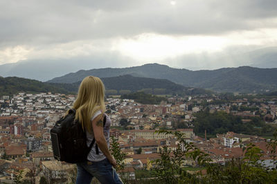 Rear view of woman standing by cityscape against sky