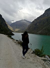 Rear view of woman by lake against mountains