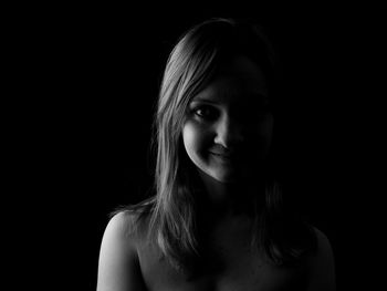 Close-up portrait of young woman against black background