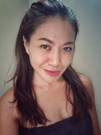 Portrait of beautiful young woman against wall