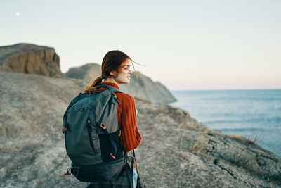 Young woman standing in sea against sky