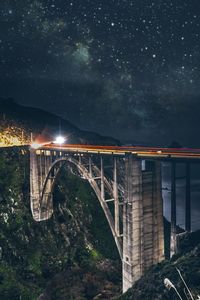 Arch bridge over river against sky at night