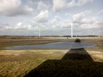 Road passing through field against cloudy sky