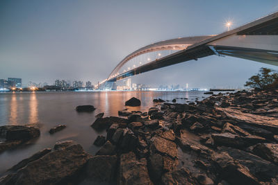 Bridge over river in city against sky at night