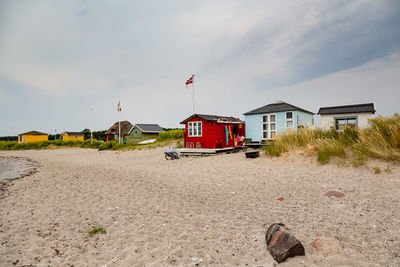 Houses on beach by buildings against sky