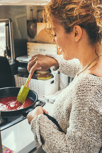 Side view of young woman holding food at home