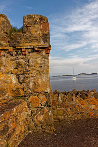 Stone wall by sea against sky