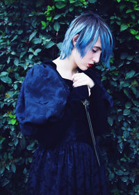 Portrait of young woman standing against plants