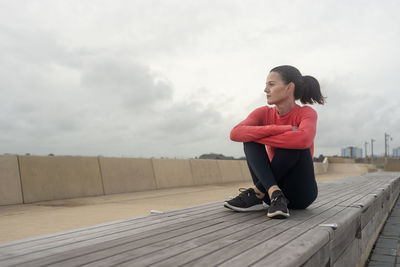 Portrait of young woman sitting on boardwalk