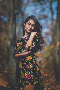 Young woman looking away while standing against tree