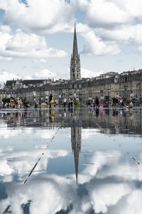 Reflection of building in water against cloudy sky