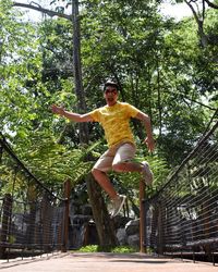 Low angle view of young man jumping against trees