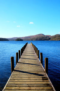 Pier over lake against clear blue sky