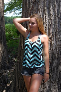 Young woman leaning on tree trunk