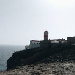 Lighthouse in sea against clear sky