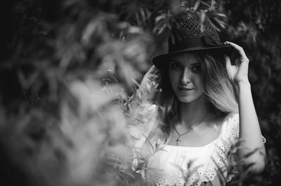 Portrait of young woman wearing hat by plants in forest