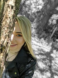 Portrait of young woman with tree trunk