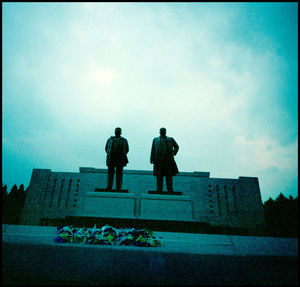 Rear view of men standing in city against sky