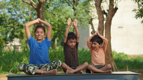 Kids doing yoga pose in the park outdoor. healthy life style concept.