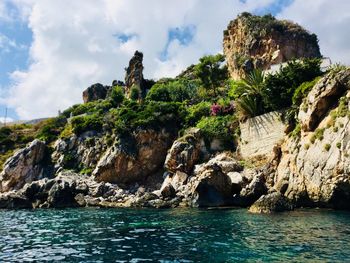 Scenic view of rocks by sea against sky