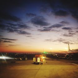 Airplane on runway against sky during sunset