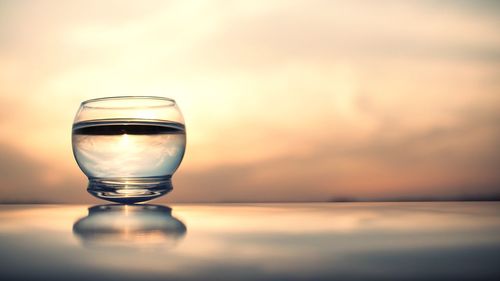 Glass fishbowl against sunset sky