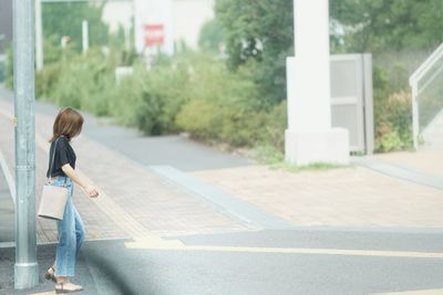 Rear view of woman walking on road in city