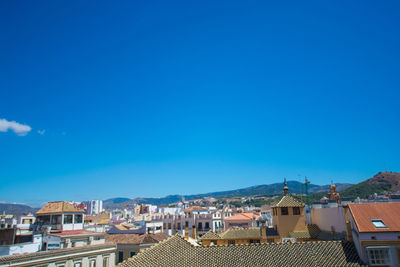 Buildings in city against clear blue sky