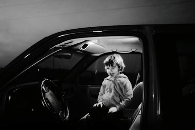 Curious happy girl looking at steering wheel in car