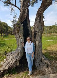 Portrait of woman standing against tree trunk