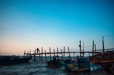 Boats moored in sea against clear blue sky