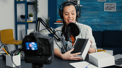 Portrait of young woman using digital tablet while standing in office