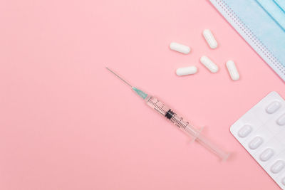 Close-up of colored pencils on table against pink background