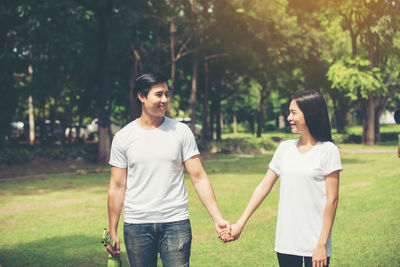 Smiling young couple holding hands while standing in park