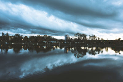 Reflection of silhouette trees on river against sky