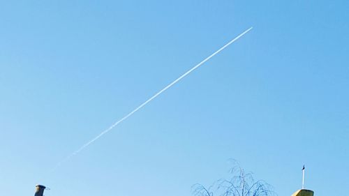 Low angle view of vapor trails against blue sky