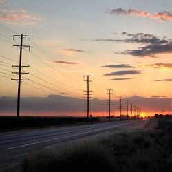 Electricity pylons on field at sunset