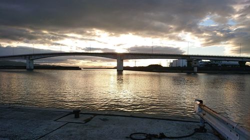 Bridge over river against sky at sunset