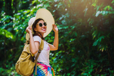 Portrait of smiling young woman wearing sunglasses standing outdoors