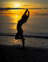 Silhouette woman standing at beach during sunset