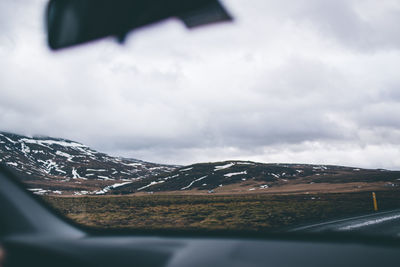 Scenic view of snowcapped mountains against sky seen through car windshield